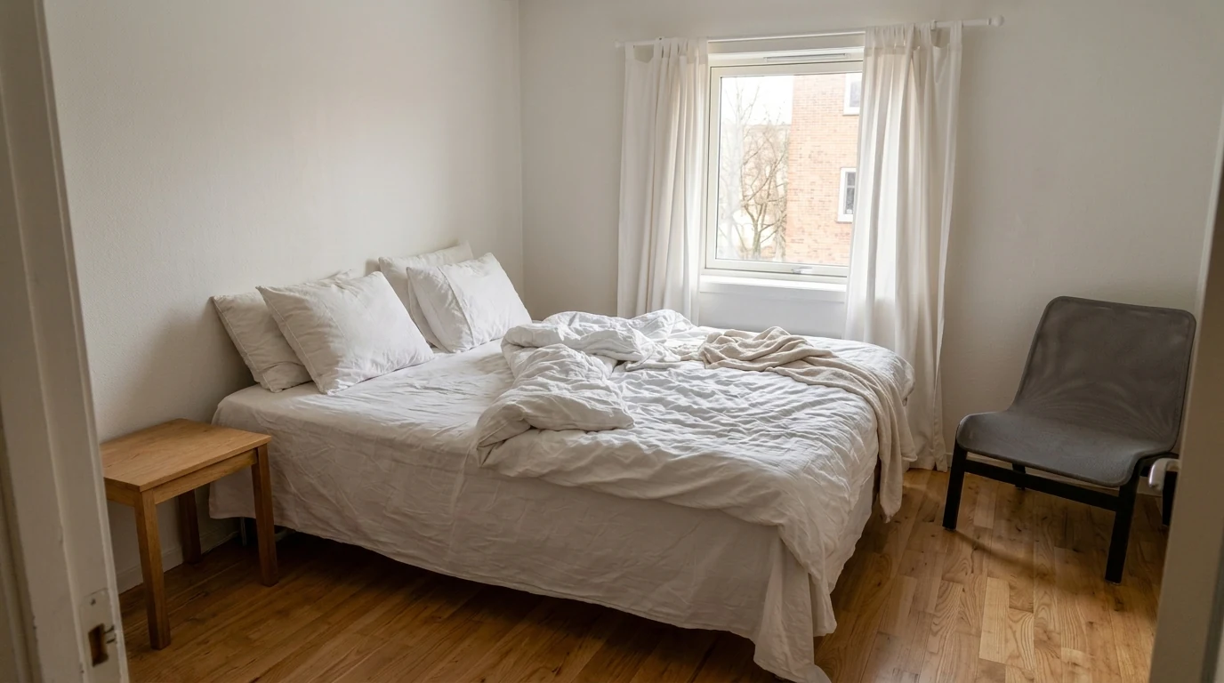 An honestly graded bedroom, light lifted and the bed made